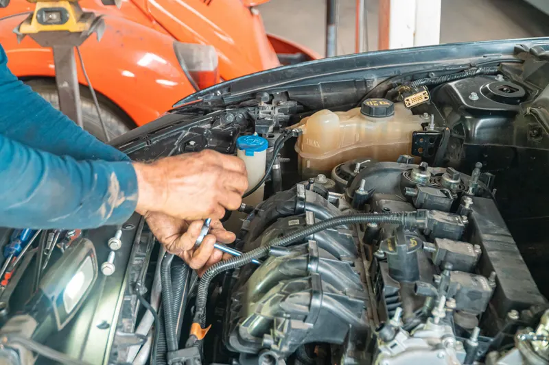 Hands working on engine bay components